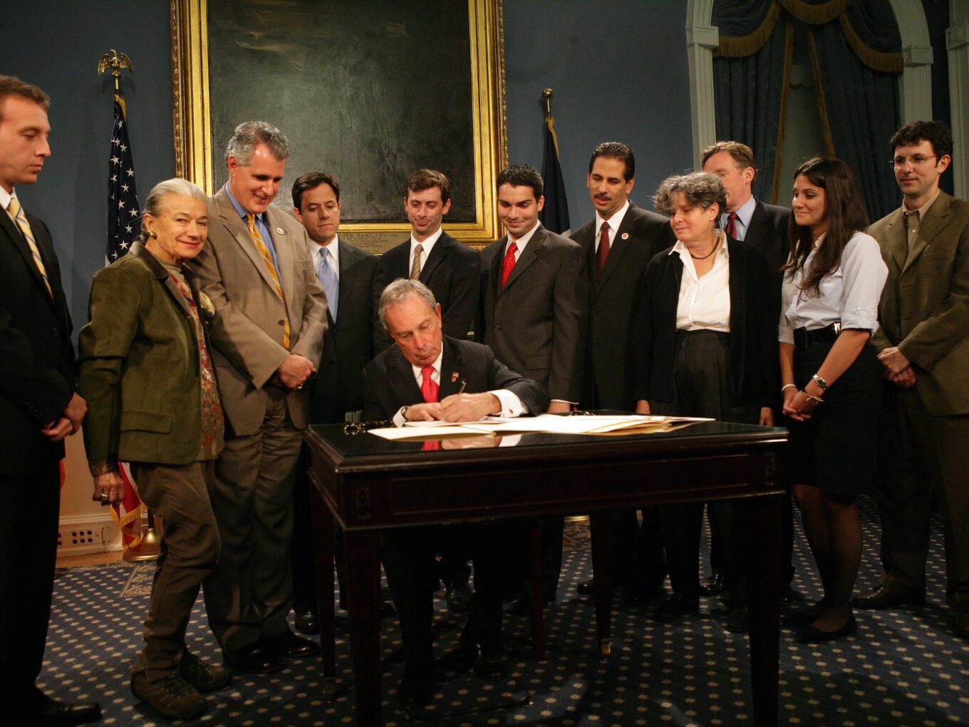 Legislator signing bill, people watching